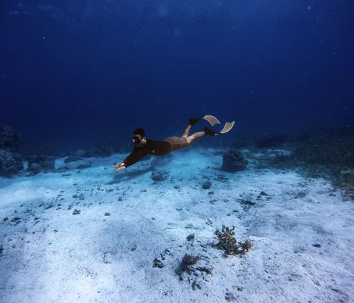 Free Underwater photograph of a snorkeler exploring the seabed with fins and mask. Stock Photo