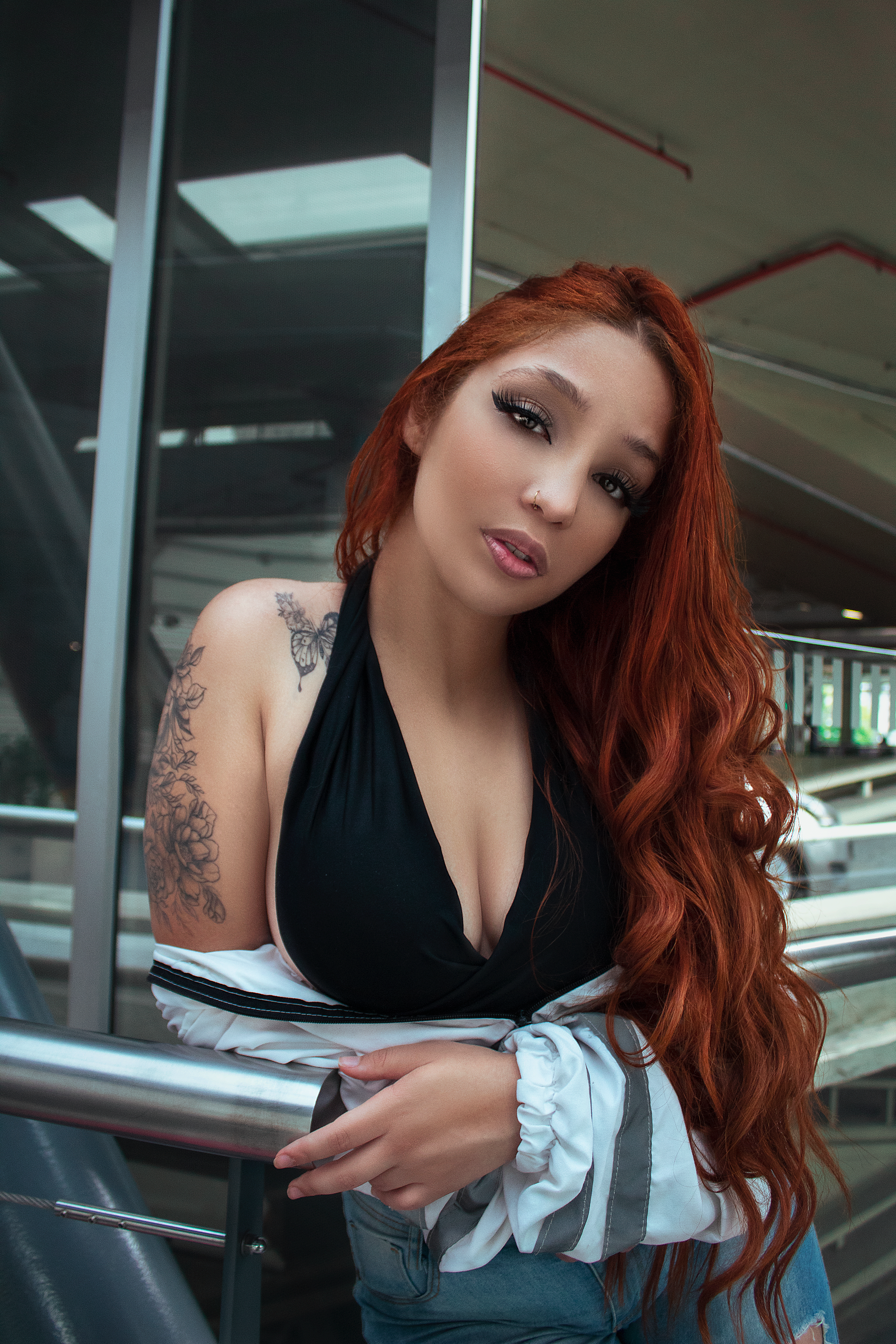 Portrait of a fashionable Latina woman with red hair and tattoos in a modern urban location in São Paulo, Brazil.