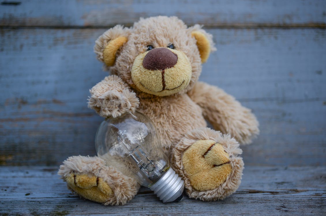 Close-Up Photography of Teddy Bear Near Light Bulb