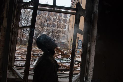 Free A person silhouetted against an open window in a dilapidated building, smoke wafts around. Stock Photo