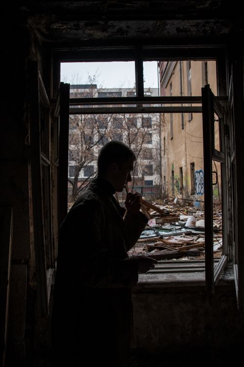 Free Silhouette of a person standing near a window in an abandoned building with a dark, eerie atmosphere. Stock Photo