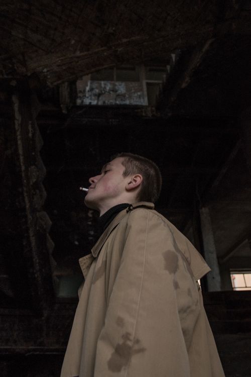 Free A side view of a man smoking indoors in a brown coat, creating an eerie atmosphere. Stock Photo