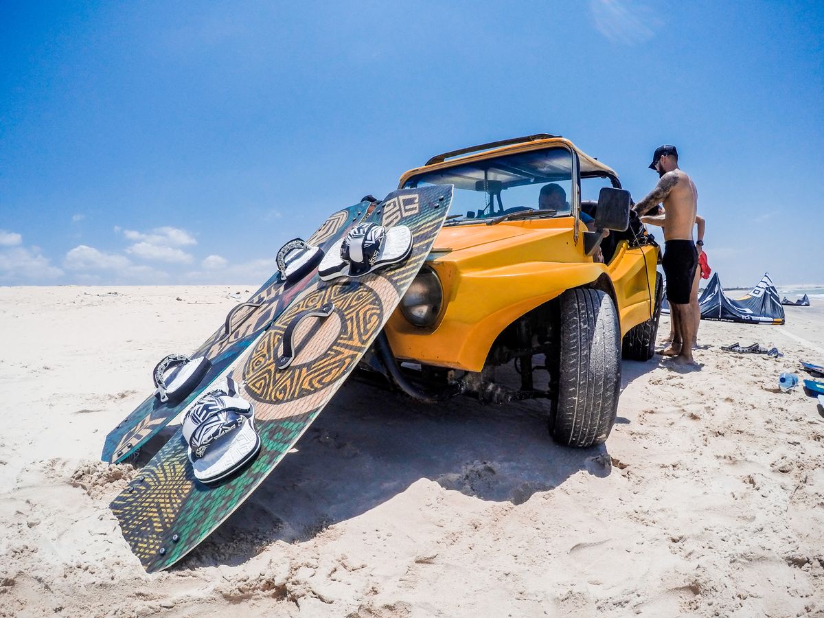 Veículo em uma praia com equipamentos de esporte