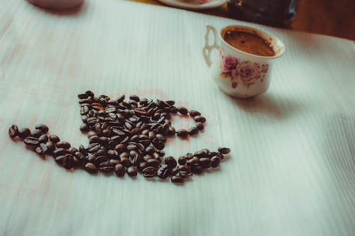 Brown Coffee Beans Beside Ceramic Mug on Table