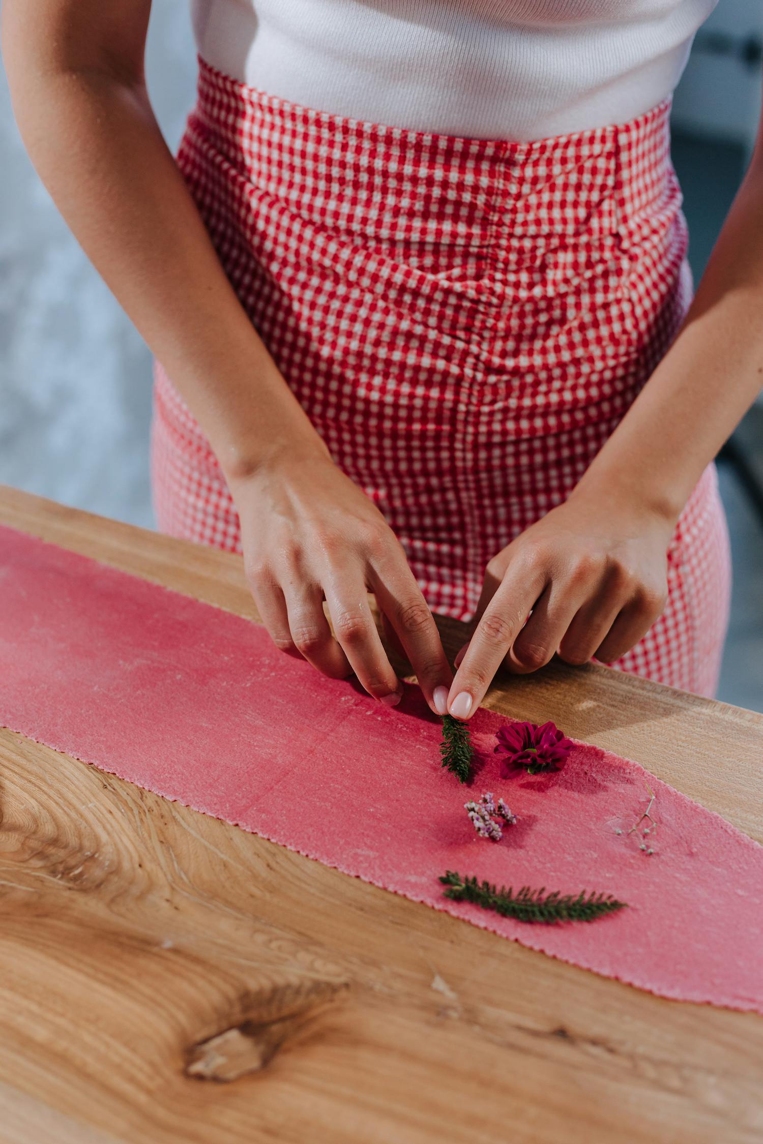 Hands arranging herbs on homemade pasta