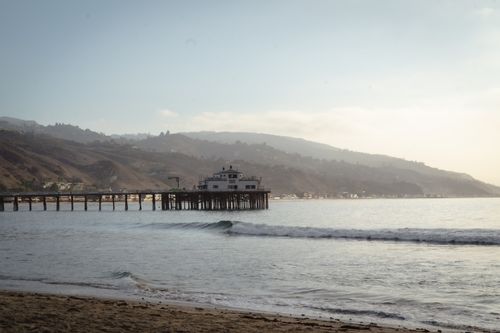Free Tranquil morning view of Malibu Pier extending into the ocean with a mountainous backdrop. Stock Photo
