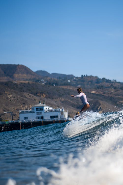 A Woman in a White Swimsuit Surfing