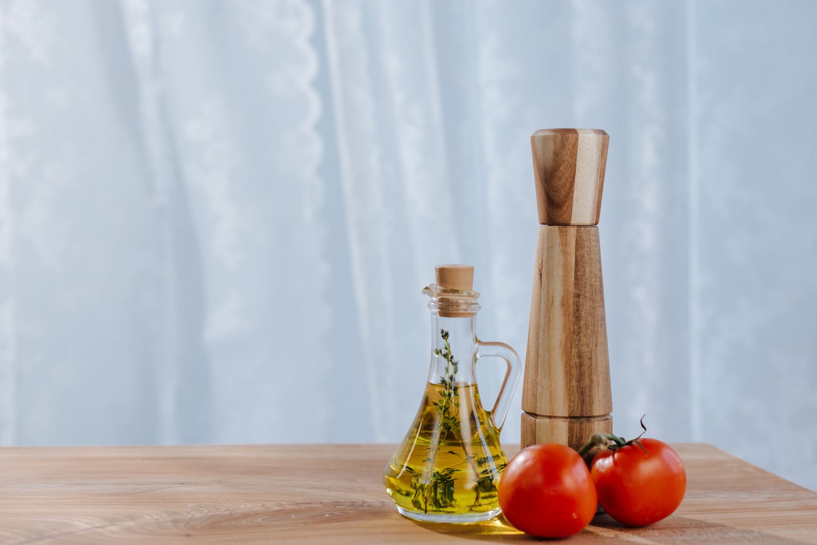 Olivový olej s rajčaty a mlýnkem na koření — prémiový olivový olej jako součást gastronomické sady nebo originální kuchyňský dárek.