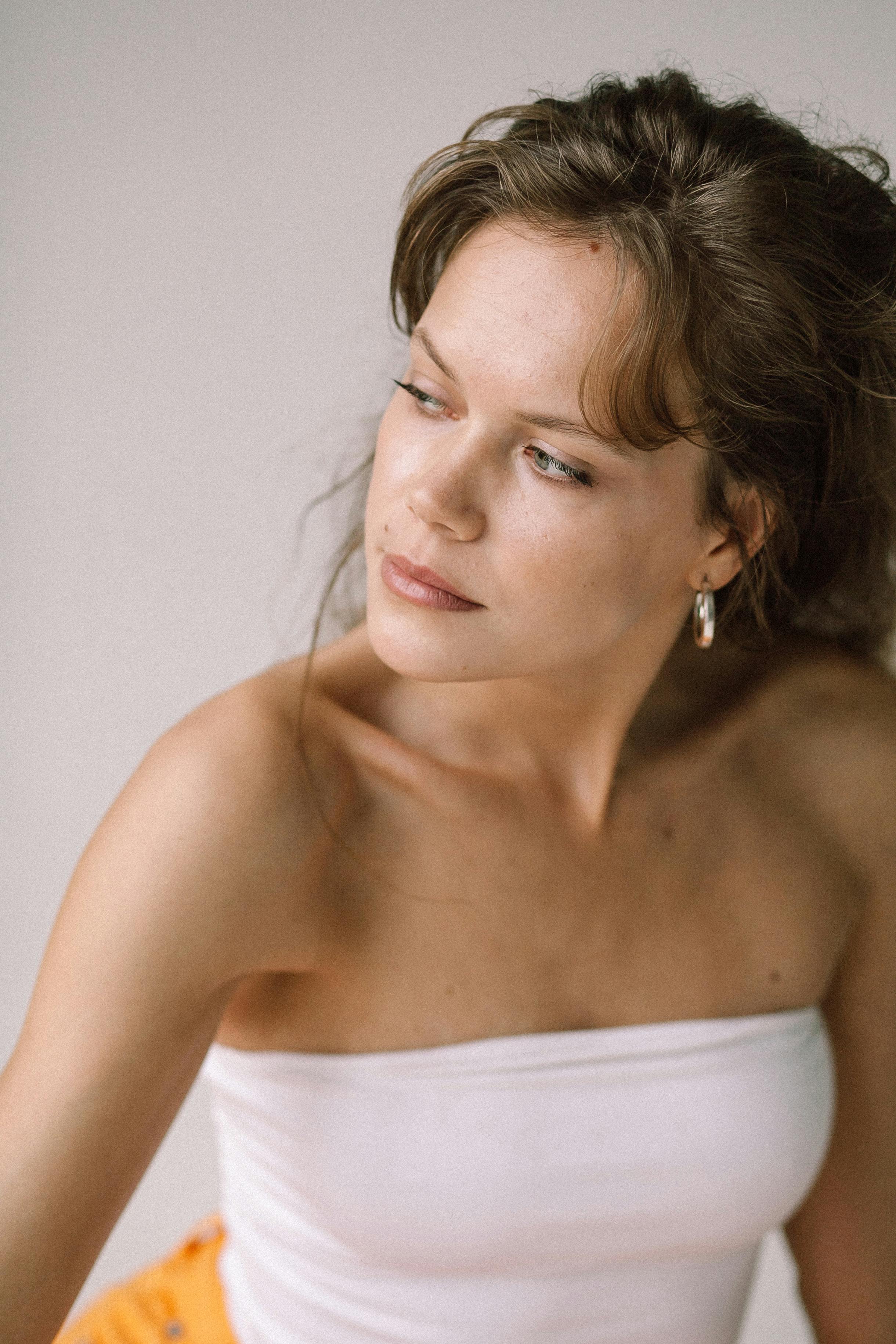 Elegant portrait of a woman in a white tube top looking over her shoulder with soft lighting.