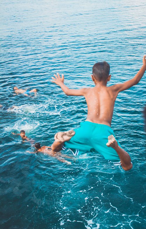 Free Energetic boys dive into blue waters, capturing the essence of summer fun in Tanauan, Philippines. Stock Photo