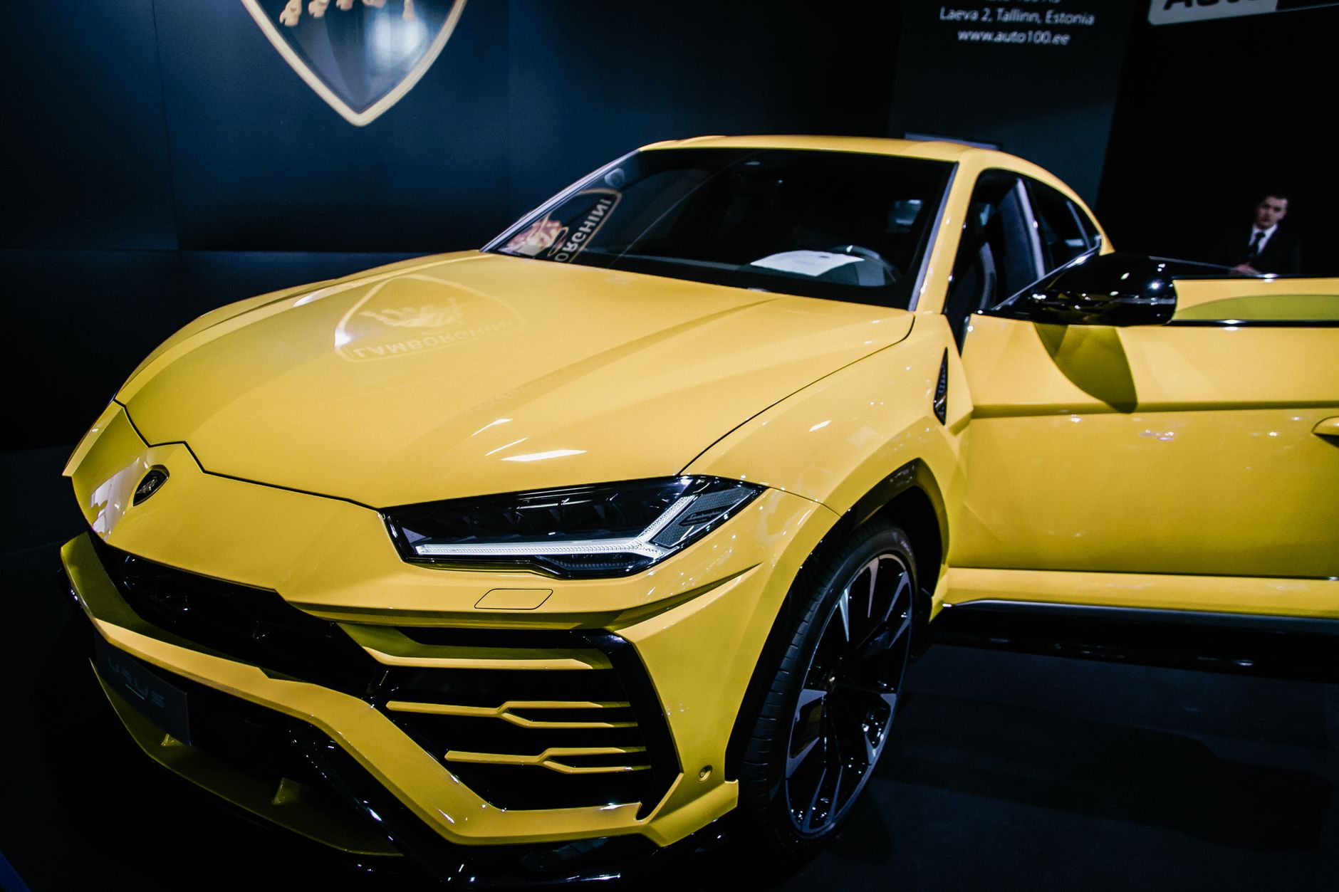 A stunning yellow luxury SUV on display at an auto show under bright lights.