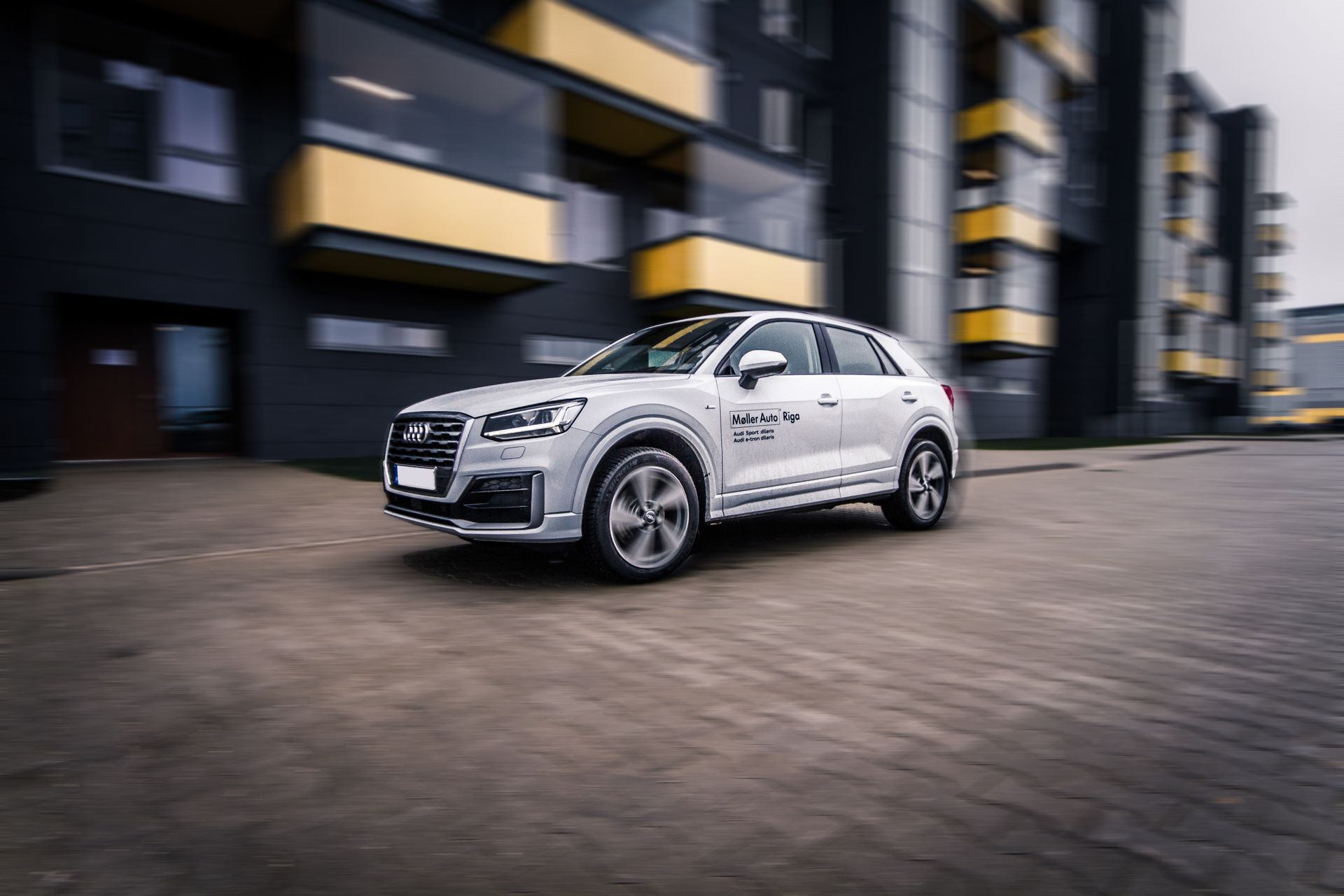 A dynamic shot of a modern Audi SUV speeding through a contemporary cityscape.