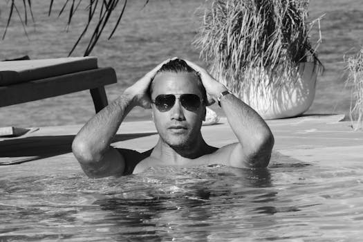 Adult male with sunglasses cooling off in a pool, enjoying a sunny day at a resort in Tanzania.