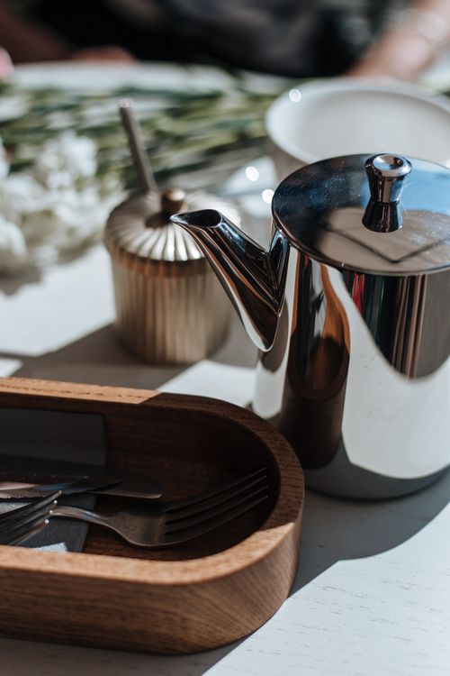 Free A stainless steel coffee pot with modern kitchen utensils on a sunlit table, creating a warm ambiance. Stock Photo