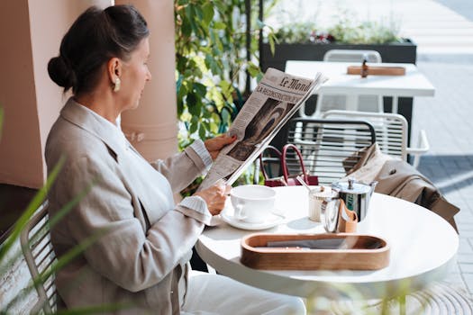 An elegant woman reads a newspaper at an outdoor cafe, enjoying a relaxing morning.