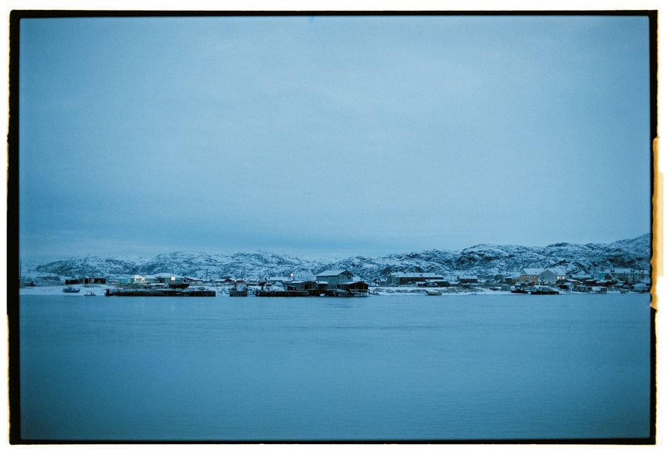 Snow-covered coastal village in Teriberka, Russia, during winter.