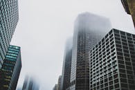 雾霭笼罩着高耸的摩天大楼，构成了戏剧性的现代城市景观
