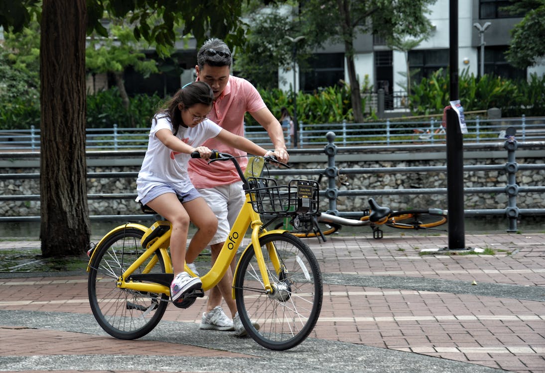 Free A Girl Riding a Bike with the Help of her Father   Stock Photo