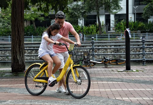 Een Meisje Op Een Fiets Met De Hulp Van Haar Vader