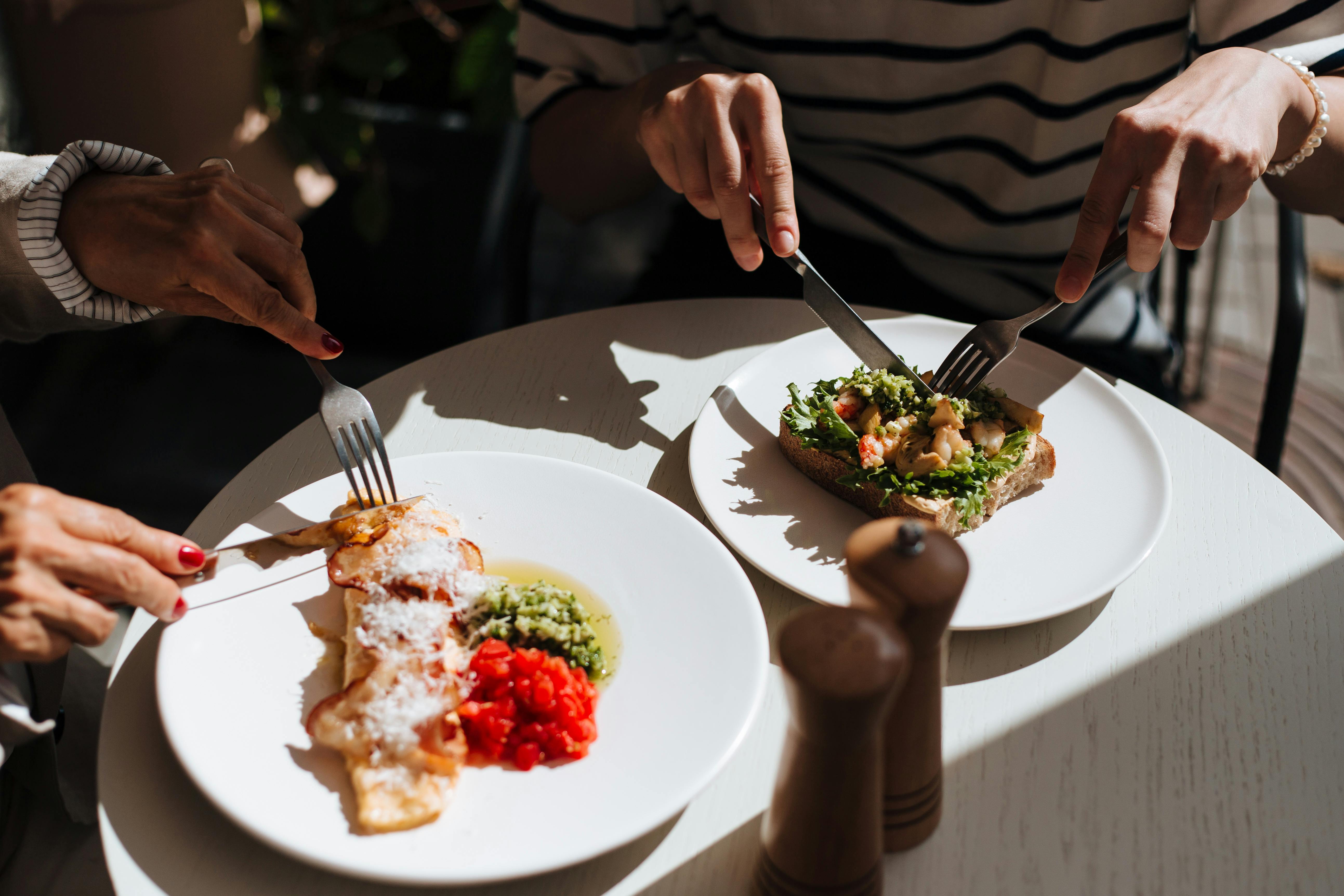 Person Slicing Food on White Ceramic Plate