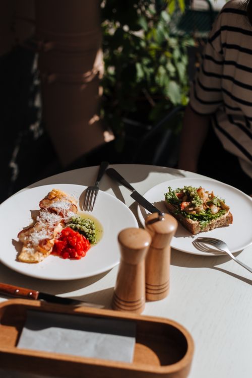 Free Two appetizing breakfast dishes with vibrant vegetables on a sunny outdoor table setting. Stock Photo