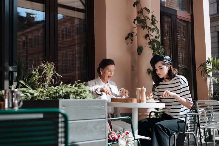 A Stylish Grandmother And Granddaughter Eating Brunch Together