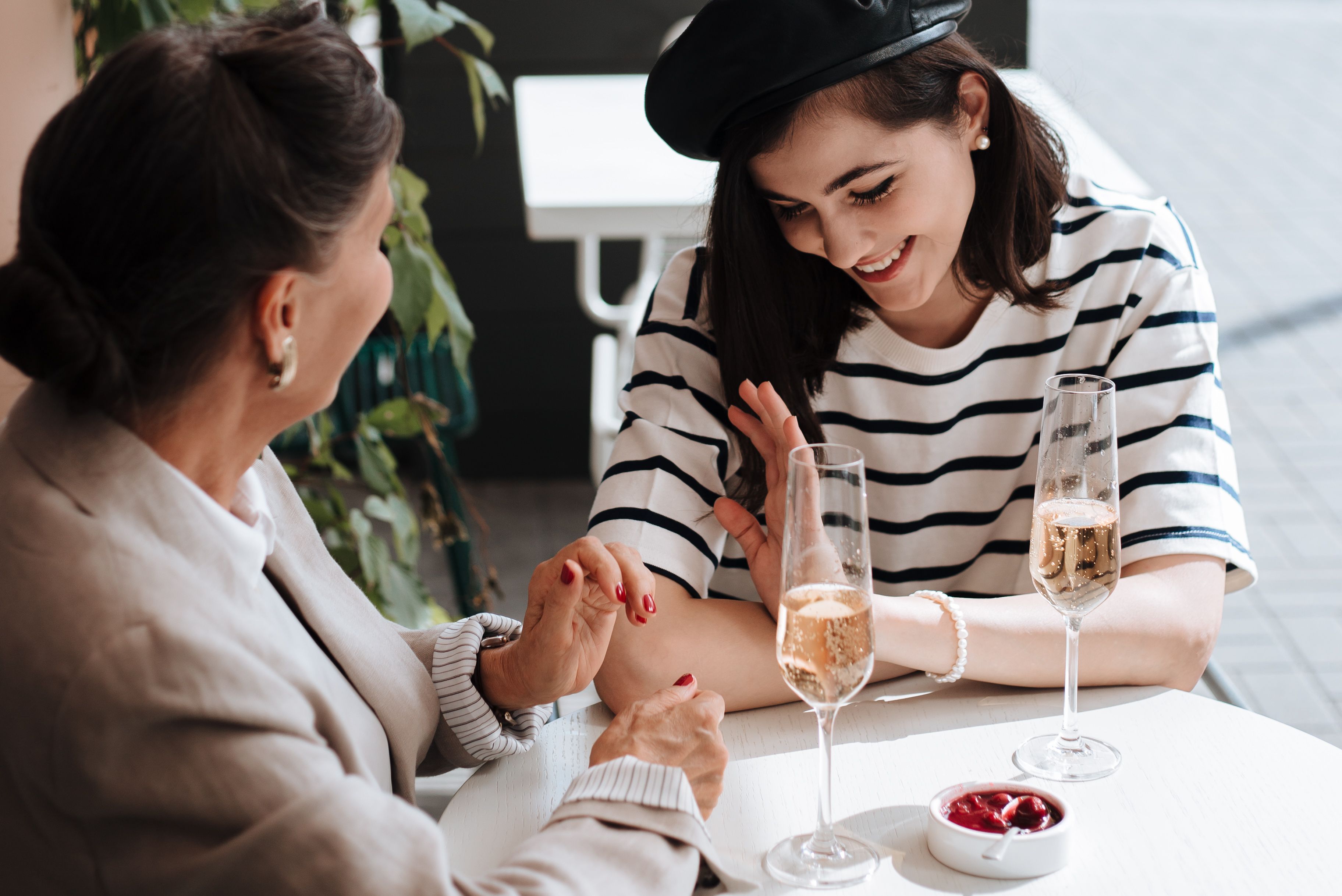 Two women enjoying champagne and a lively conversation at an outdoor café.