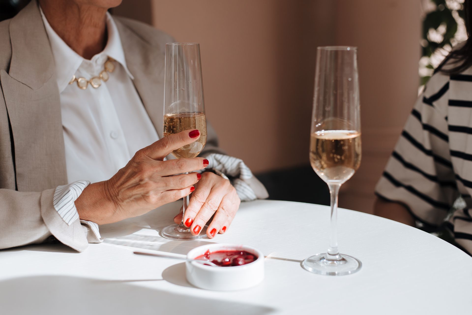 Close-up of two people with champagne glasses at a round table during a social gathering.