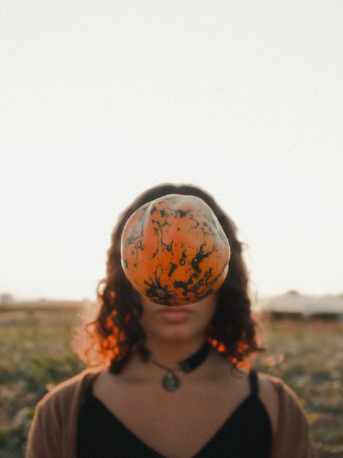 A Pumpkin Midair Covering a Woman's Face