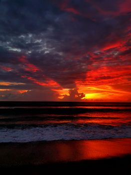 A breathtaking view of a dramatic sunset over the ocean, capturing vibrant red and orange hues.