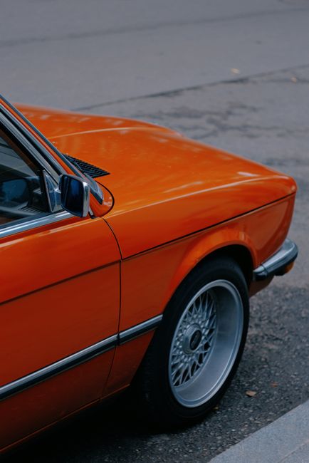 Close-up of a vintage orange car parked on the pavement in Kyiv. A classic street scene.