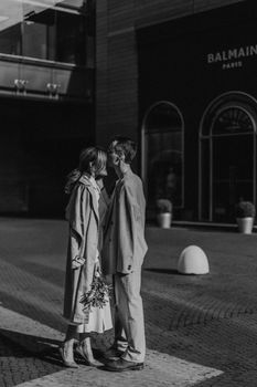 A couple shares a romantic embrace in an urban setting, captured in black and white.
