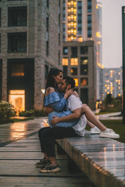 Free A loving couple sits close on a city bench during a warm, twilight evening. Stock Photo