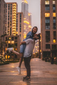 Happy couple embracing on a city sidewalk during evening twilight, city lights glowing.