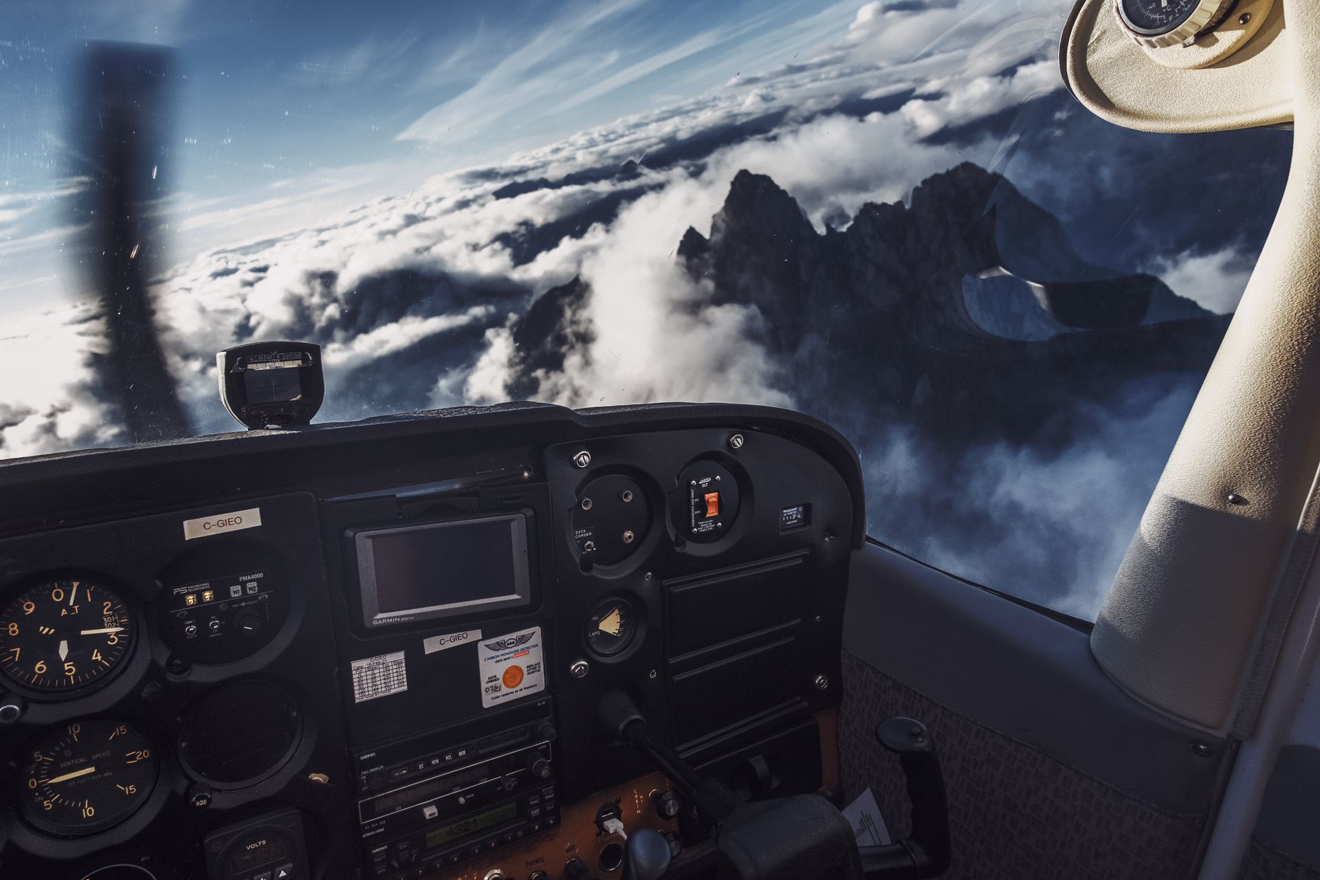Experience a breathtaking aerial view over BC, Canada from the cockpit of a flying aircraft amidst clouds.