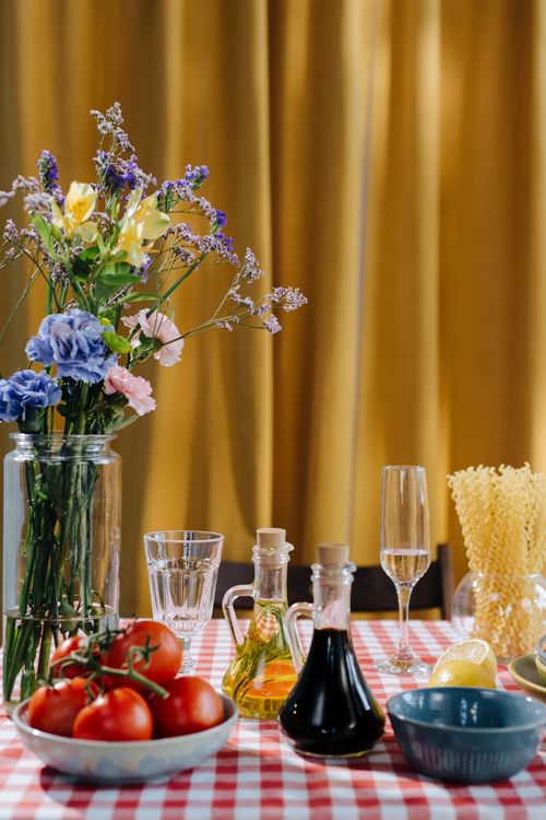 Free A vibrant table setting featuring Italian ingredients and flowers on a gingham cloth. Stock Photo