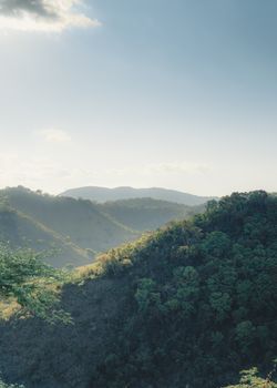 Scenic view of green hills and lush forest under a clear summer sky.