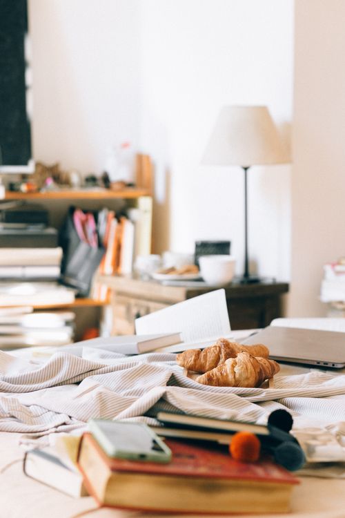 Free Inviting workspace featuring a laptop, croissants, and books, perfect for a productive morning. Stock Photo