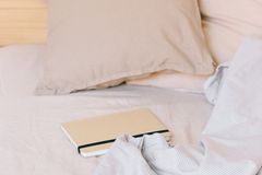 A tranquil bedroom scene with cozy pillows, notebook, and soft bedding.
