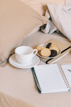 Warm morning scene with tea, biscuits, and a planner on a bed.