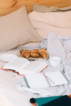 A peaceful morning scene with breakfast in bed, croissants, and open books.