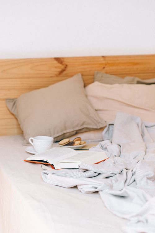 Free Relaxing scene of a cozy bed with book, coffee, and cookies for a perfect reading time. Stock Photo