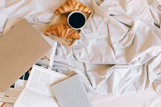Relaxing morning scene with croissants and coffee on a bed, ideal for lifestyle themes.