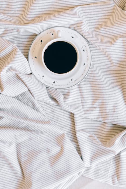 A Ceramic Cup with Black Coffee on Stripes Blanket