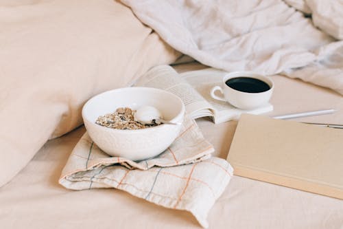 Bowl of Granola Near a Book and Cup of Black Coffee