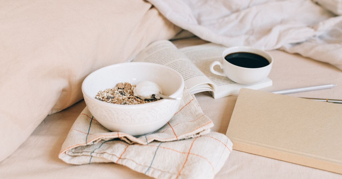 A cup of coffee next to a notebook with scribbled sports stats and a half-eaten granola bar