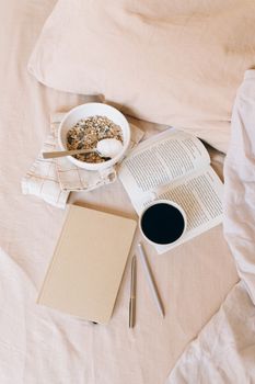 Cozy morning scene with a cup of coffee, open book, and granola on a soft fabric.
