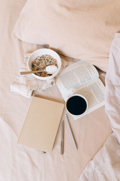 Free Cozy morning scene with a cup of coffee, open book, and granola on a soft fabric. Stock Photo