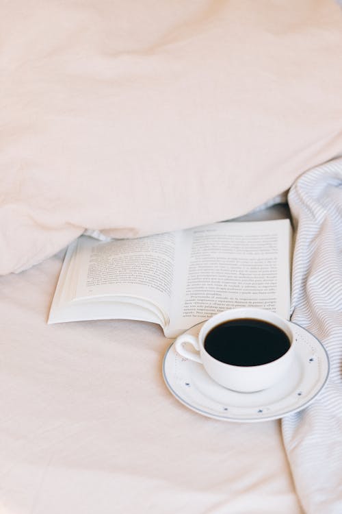 Cup of Coffee and Book on a Bed