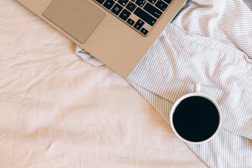 Laptop Beside the Ceramic White Cup With Black Liquid